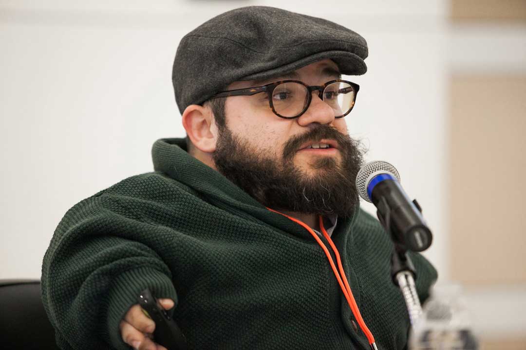 Joseph Stramondo at a microphone with a remote control in his hand